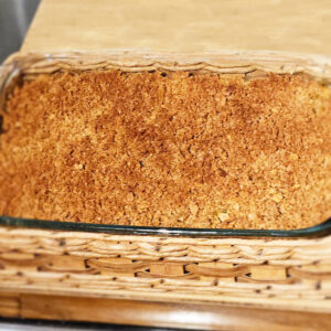 Vegan baked macaroni and cheese in glass casserole dish in wicker basket